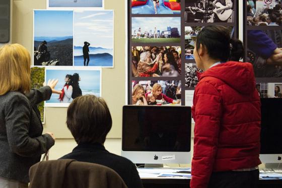 图为一群妇女在设计师办公桌上方的一面墙上查看印刷照片. 