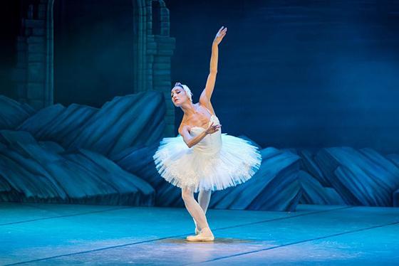 一名芭蕾舞女演员身穿白色戏服，头戴头饰，在天鹅湖翩翩起舞. 