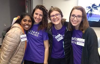 四名波胆网站的女学生穿着紫色的查塔姆t恤微笑着合影.